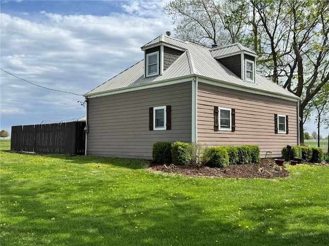 view of side of home featuring a yard, metal roof, and fence