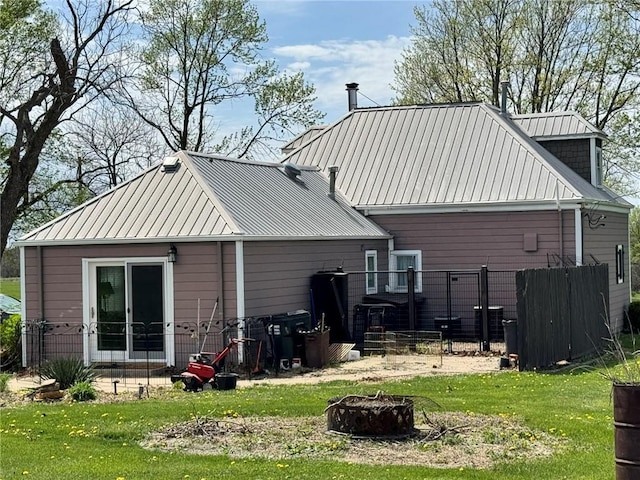 back of house with a yard, a standing seam roof, and metal roof