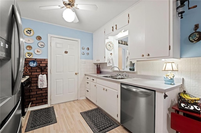 kitchen with white cabinets, appliances with stainless steel finishes, a sink, and light countertops