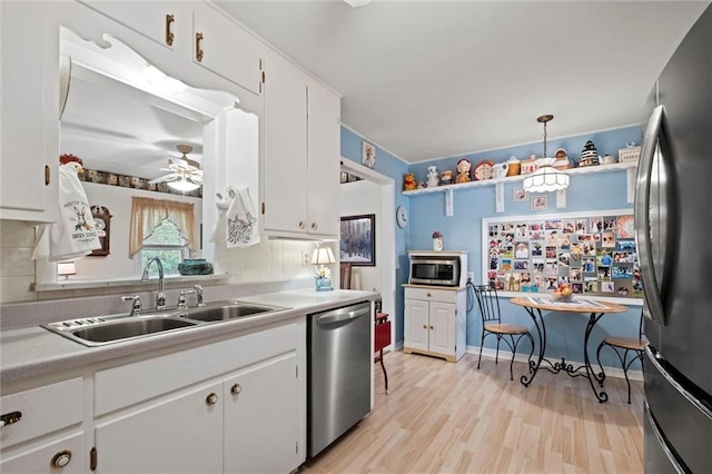 kitchen with white cabinets, stainless steel appliances, a sink, tasteful backsplash, and light countertops