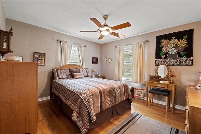 bedroom featuring baseboards, wood finished floors, and multiple windows