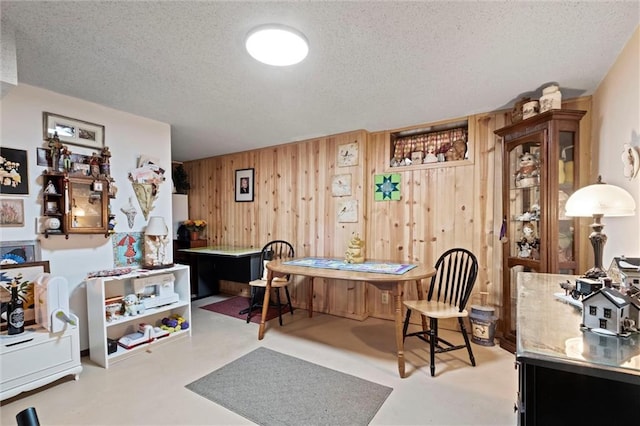 dining space featuring wooden walls and a textured ceiling