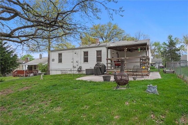 rear view of property with a ceiling fan, fence, a yard, a patio area, and an outdoor fire pit