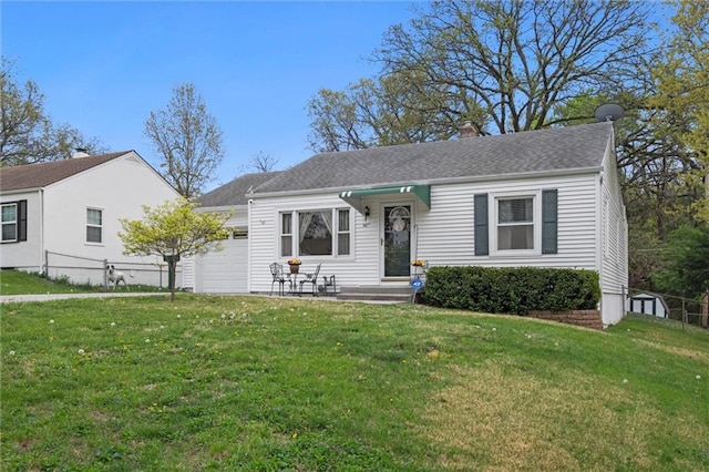 view of front of home with a front lawn, roof with shingles, and a garage