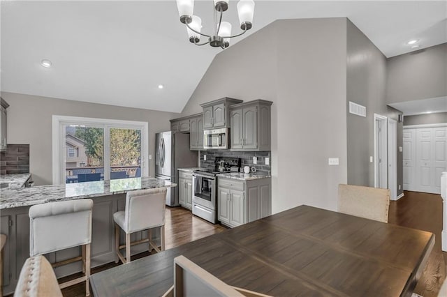 16754 W 156th Ter, Olathe, KS 66062 - kitchen with stainless steel appliances, a chandelier, decorative backsplash, dark wood-type flooring, and high vaulted ceiling