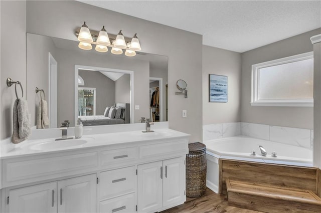 16754 W 156th Ter, Olathe, KS 66062 - ensuite bathroom with double vanity, wood finished floors, a bath, and a textured ceiling