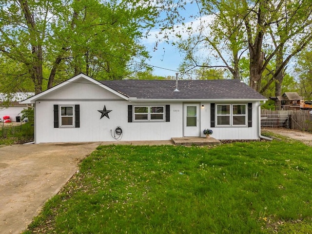 ranch-style house with concrete driveway, a front lawn, fence, and roof with shingles