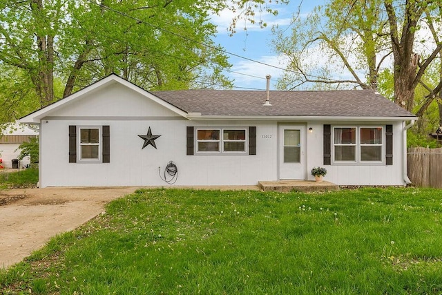 ranch-style home featuring a shingled roof, a front yard, and fence