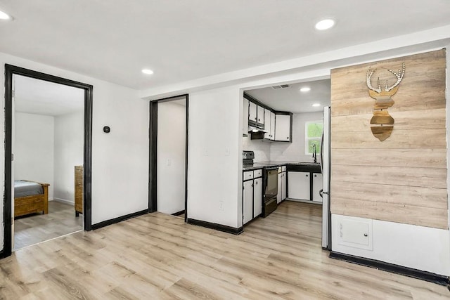 kitchen featuring recessed lighting, dark countertops, black range with electric stovetop, freestanding refrigerator, and light wood-type flooring