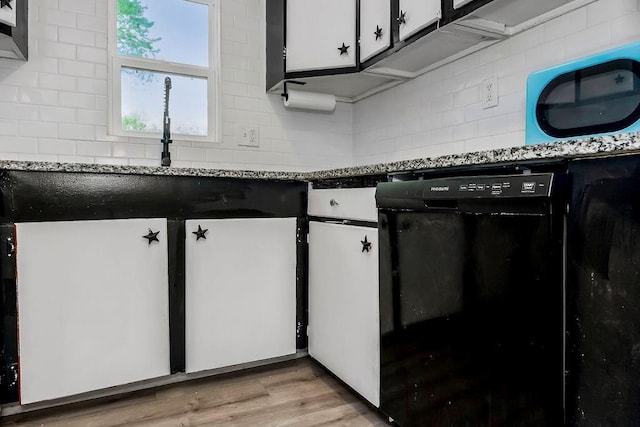 kitchen featuring dark countertops, white cabinets, light wood-style floors, backsplash, and black dishwasher