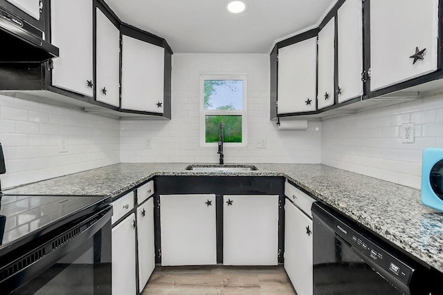 kitchen with black appliances, decorative backsplash, under cabinet range hood, and a sink