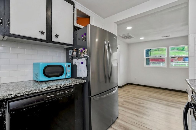 kitchen featuring visible vents, dishwasher, freestanding refrigerator, and tasteful backsplash