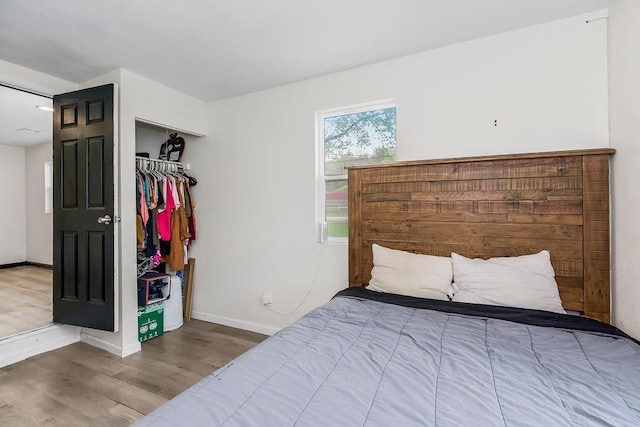 bedroom featuring wood finished floors, a closet, and baseboards