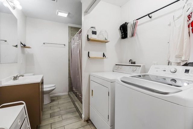clothes washing area featuring laundry area, wood finish floors, washer and dryer, and a sink