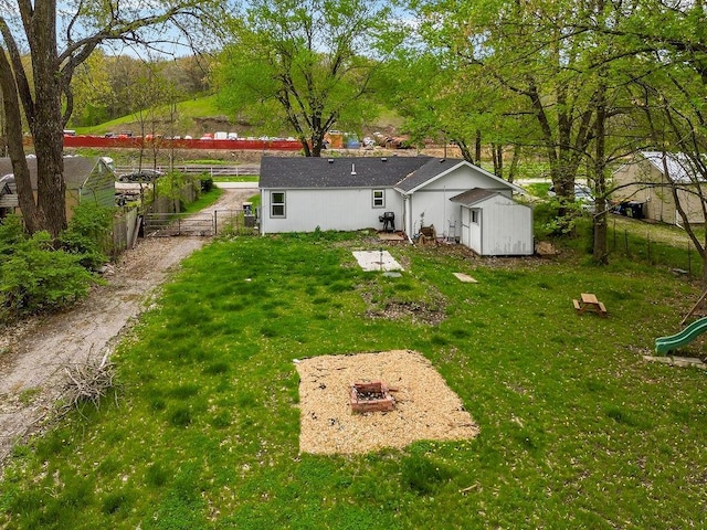 back of property featuring a lawn, an outdoor structure, fence, and a playground