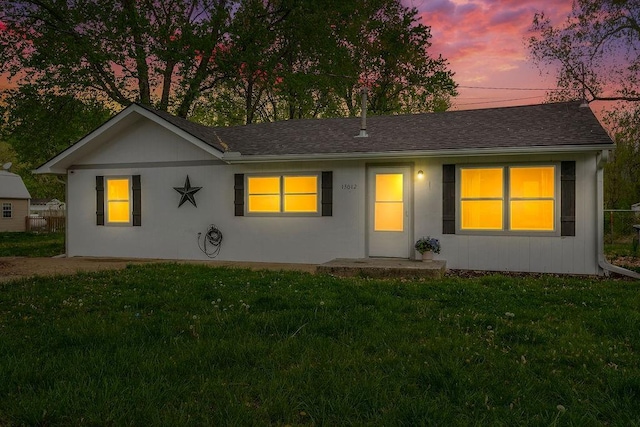 ranch-style house with a yard and a shingled roof