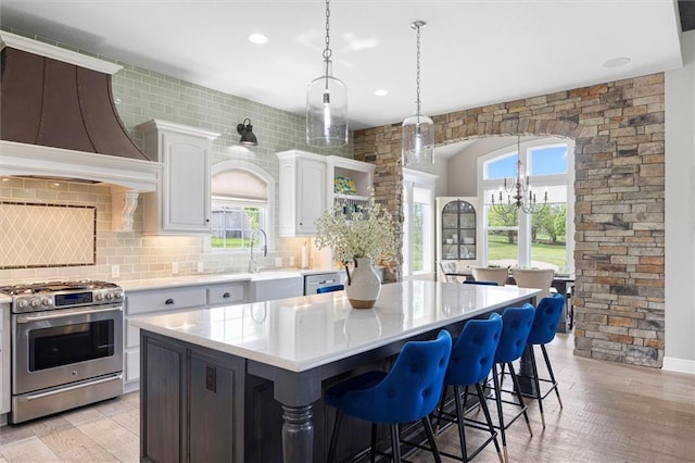 24212 W 69th St, Shawnee, KS 66226 - kitchen with stainless steel gas stove, light countertops, custom range hood, a sink, and a center island