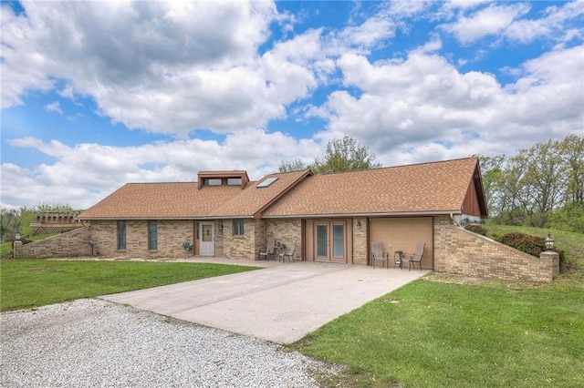 24101 E 223rd St, Harrisonville, MO 64701 - back of house featuring an attached garage, brick siding, concrete driveway, french doors, and a lawn