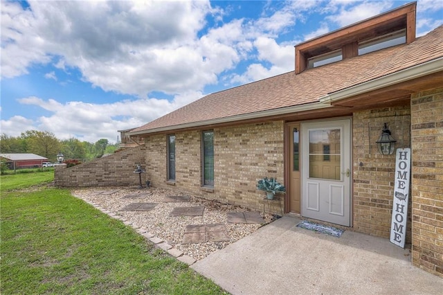 24101 E 223rd St, Harrisonville, MO 64701 - doorway to property featuring a yard, brick siding, and a shingled roof