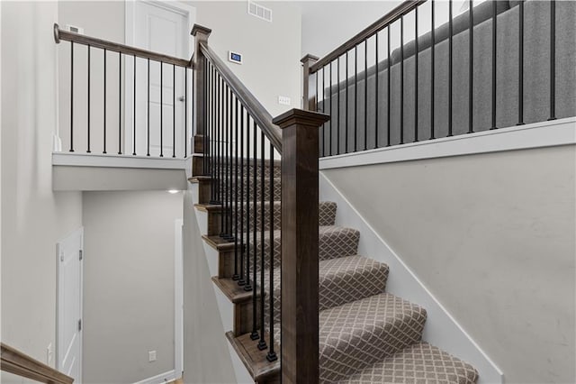 staircase with a high ceiling and visible vents