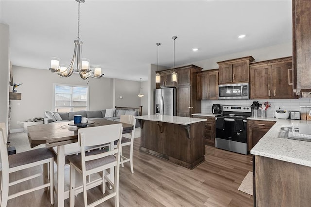kitchen with stainless steel appliances, a center island, open floor plan, an inviting chandelier, and backsplash