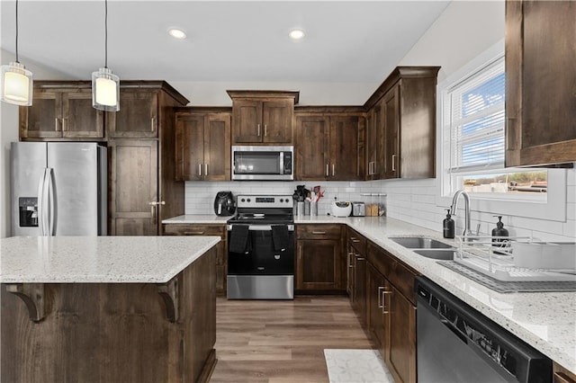 kitchen with dark brown cabinetry, appliances with stainless steel finishes, wood finished floors, and a sink