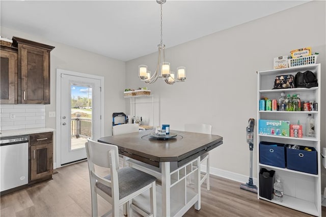 dining space with light wood-style floors, baseboards, and an inviting chandelier