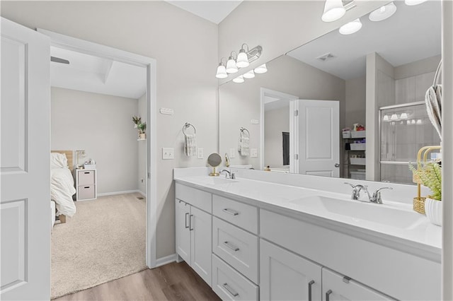 full bathroom with double vanity, wood finished floors, visible vents, and a sink