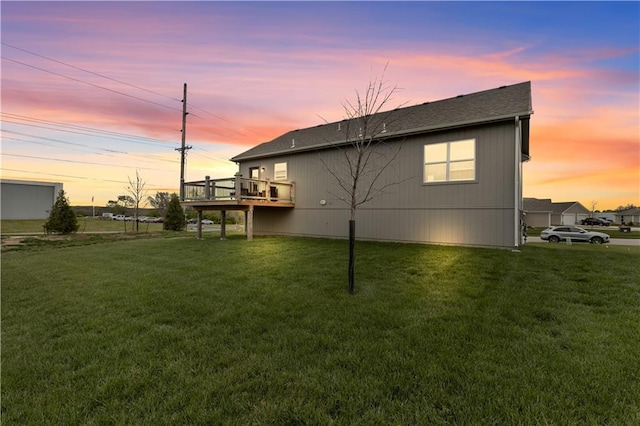back of property featuring a lawn, roof with shingles, and a deck