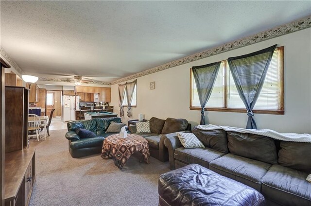 living room featuring a textured ceiling, a ceiling fan, and light carpet