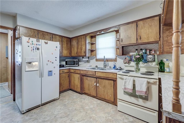 kitchen with light countertops, brown cabinetry, a sink, and white appliances