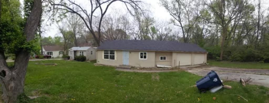 exterior space featuring stucco siding, an attached garage, aphalt driveway, and a yard