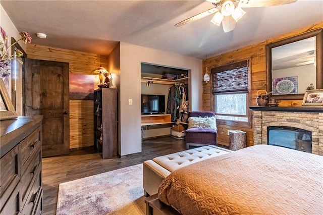 185 SW 51st Rd, Warrensburg, MO 64093 - bedroom featuring wood walls, a closet, wood finished floors, a fireplace, and a ceiling fan