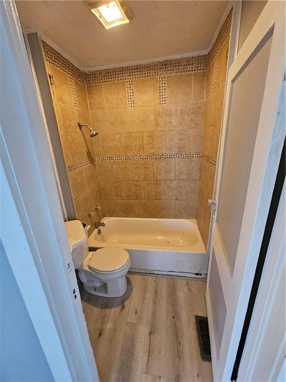 4410 Myrtle Ave, Kansas City, MO 64130 - full bath with visible vents, wood finished floors, bathtub / shower combination, and toilet