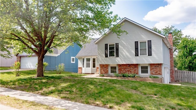 tri-level home with a chimney, brick siding, a garage, and driveway