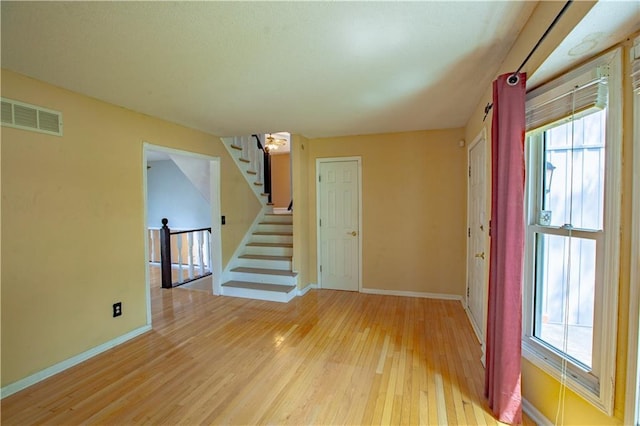 spare room featuring hardwood / wood-style floors, baseboards, and stairway