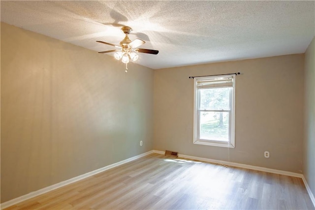 unfurnished room with light wood-type flooring, ceiling fan, a textured ceiling, and baseboards
