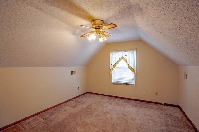 bonus room featuring light carpet, a textured ceiling, a ceiling fan, lofted ceiling, and baseboards