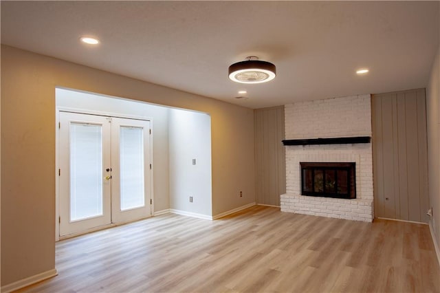 unfurnished living room with light wood-style floors, french doors, a fireplace, baseboards, and recessed lighting