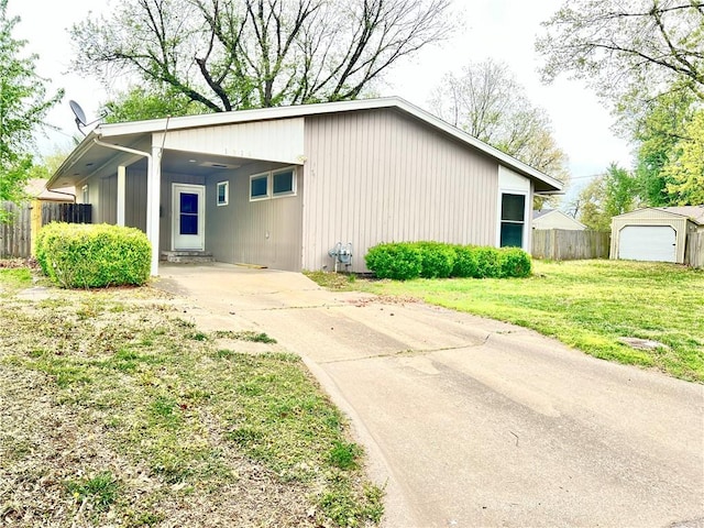 view of outbuilding featuring concrete driveway, fence, and a carport