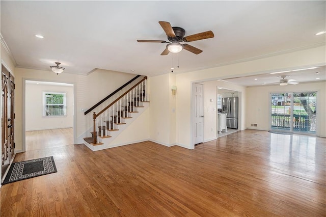 10100 El Monte St, Overland Park, KS 66207 - unfurnished living room featuring ceiling fan, crown molding, wood finished floors, stairway, and baseboards