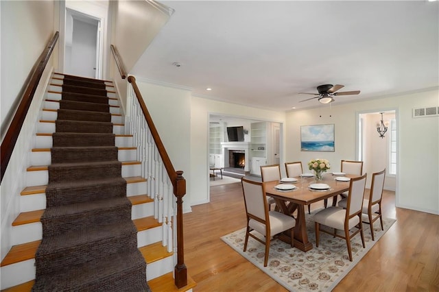 10100 El Monte St, Overland Park, KS 66207 - dining space with a ceiling fan, visible vents, a warm lit fireplace, stairs, and light wood-style flooring