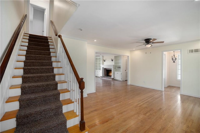 10100 El Monte St, Overland Park, KS 66207 - stairway with visible vents, wood finished floors, baseboards, ceiling fan, and a warm lit fireplace