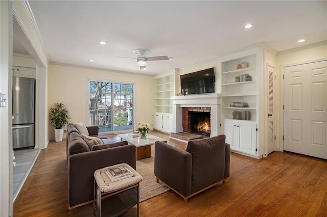 10100 El Monte St, Overland Park, KS 66207 - living room with crown molding, ceiling fan, wood finished floors, and a fireplace