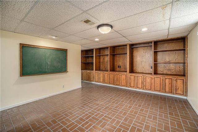 10100 El Monte St, Overland Park, KS 66207 - finished below grade area with baseboards, brick floor, visible vents, and a paneled ceiling