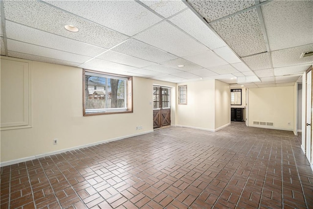 10100 El Monte St, Overland Park, KS 66207 - basement with baseboards, visible vents, a paneled ceiling, and brick floor