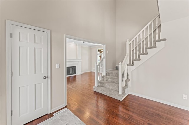 1010 SW Cross Creek Dr, Grain Valley, MO 64029 - entrance foyer with wood finished floors, stairs, a glass covered fireplace, a high ceiling, and baseboards
