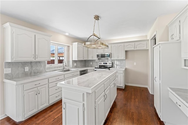 1010 SW Cross Creek Dr, Grain Valley, MO 64029 - kitchen with white cabinets, stainless steel appliances, a sink, backsplash, and a kitchen island