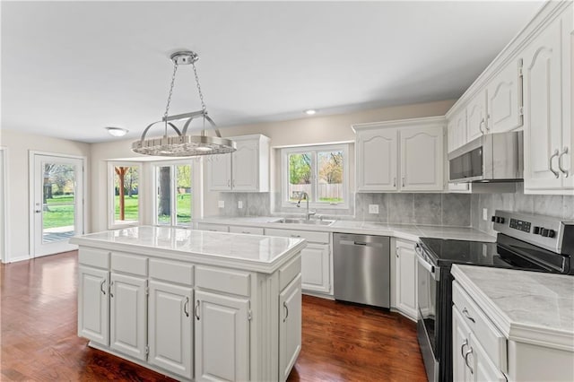 1010 SW Cross Creek Dr, Grain Valley, MO 64029 - kitchen with a center island, a sink, white cabinetry, decorative backsplash, and appliances with stainless steel finishes