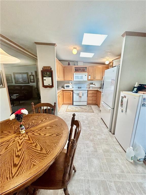 171 E 5th St, Schell City, MO 64783 - interior space featuring light brown cabinetry, a skylight, white appliances, crown molding, and light countertops